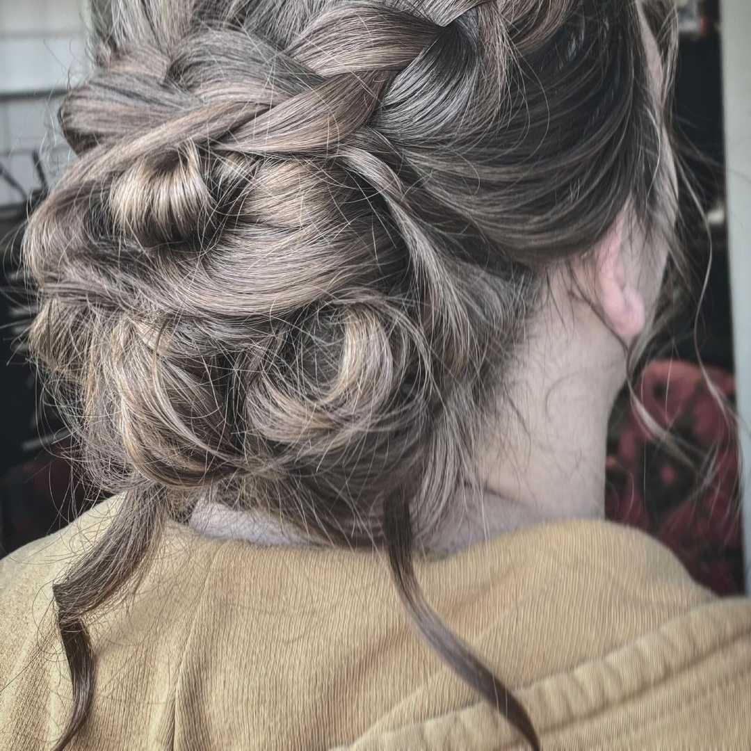 a braided updo into a thick bun with loose strands